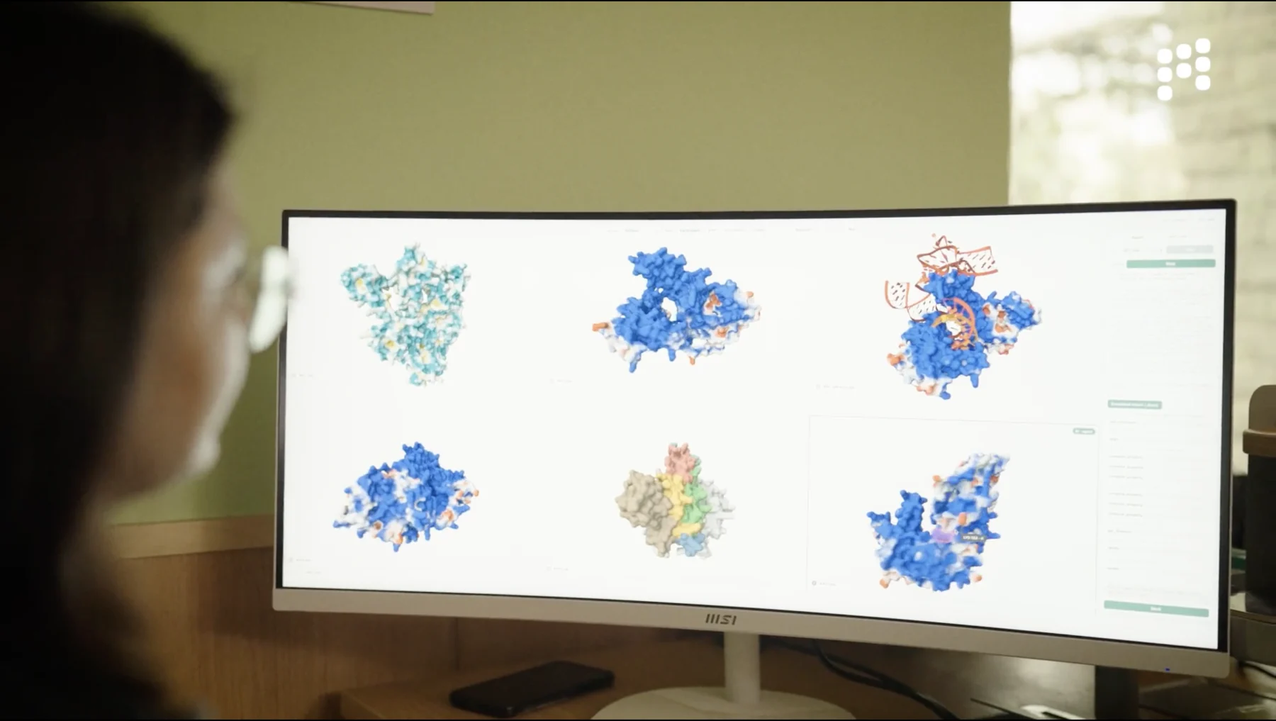 Researcher reviewing protein designs on a monitor